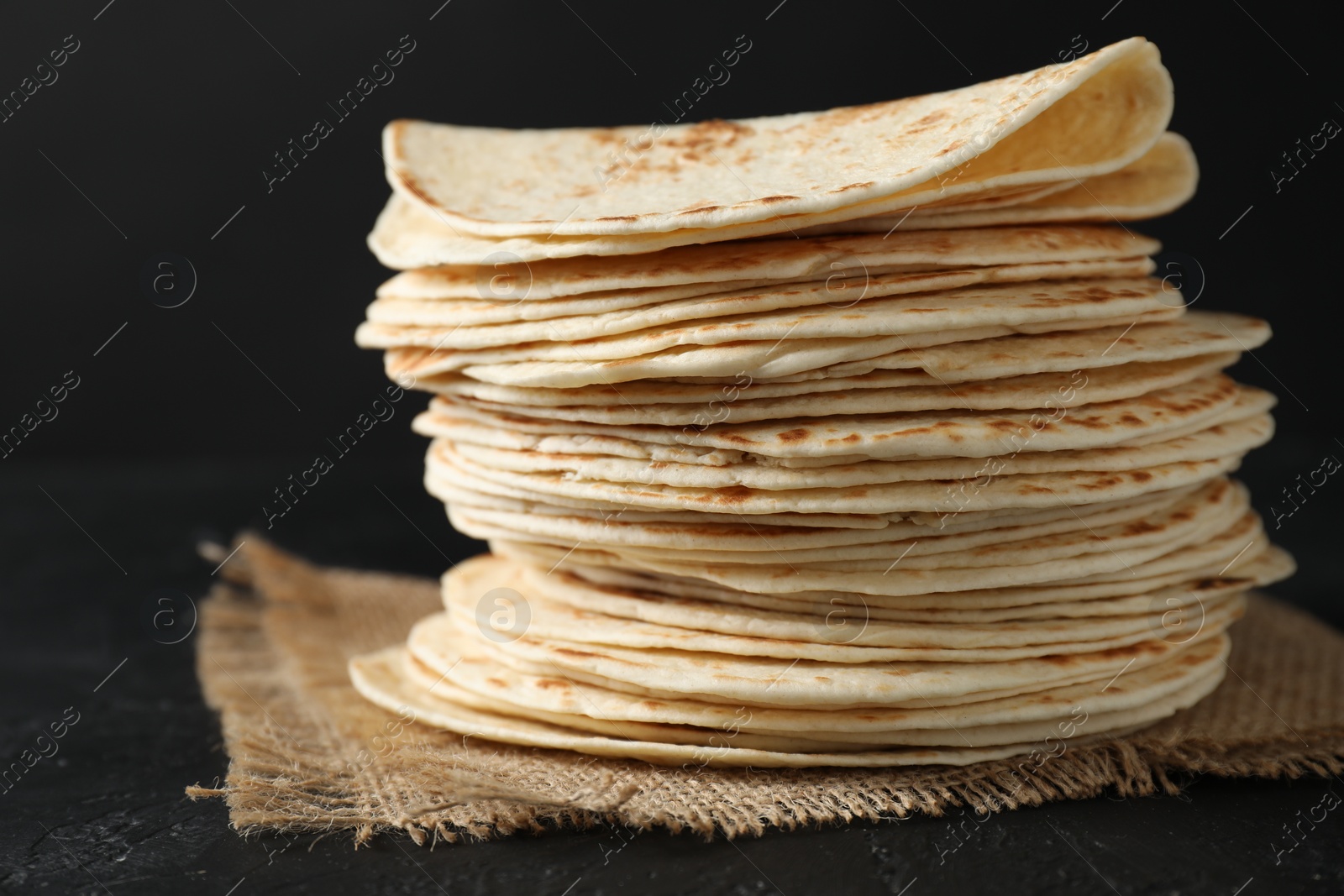 Photo of Stack of tasty homemade tortillas on black table