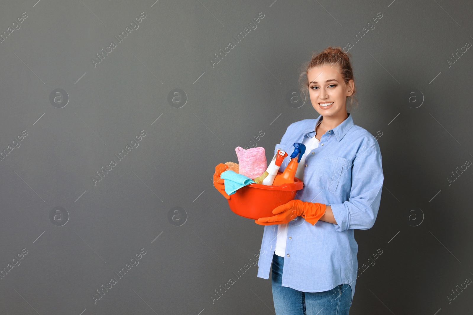 Photo of Woman with cleaning supplies on grey background