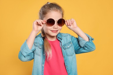Photo of Girl in stylish sunglasses on orange background