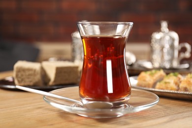 Photo of Traditional Turkish tea in glass on wooden table, closeup