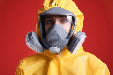 Photo of Woman wearing chemical protective suit on red background, closeup. Virus research