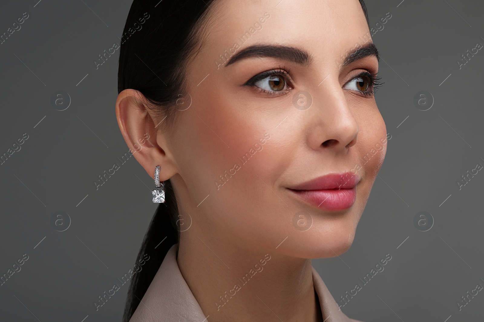 Photo of Beautiful young woman with elegant earrings on dark grey background, closeup