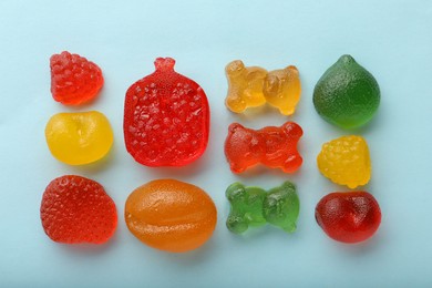 Photo of Mix of different delicious gummy candies on light blue background, flat lay