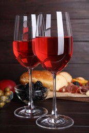 Glasses of delicious rose wine and snacks on wooden table