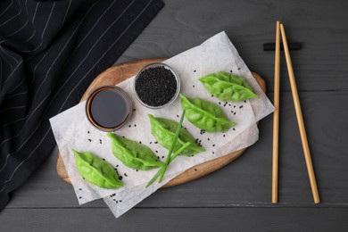 Photo of Delicious green dumplings (gyozas) served on grey wooden table, flat lay