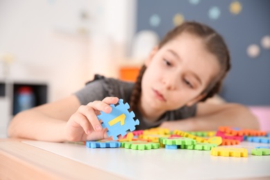 Photo of Little girl with autistic disorder playing at home, closeup of puzzles