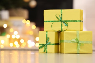 Photo of Beautifully wrapped gift boxes against blurred festive lights, space for text. Christmas celebration