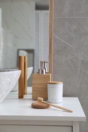 Photo of Stone vessel sink with faucet and toiletries on white countertop in bathroom