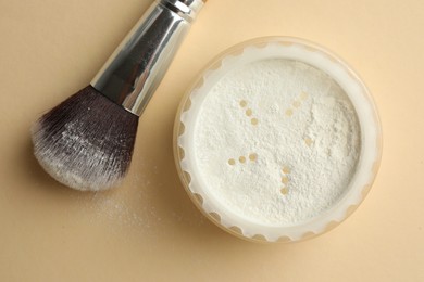 Photo of Rice loose face powder and makeup brush on beige background, flat lay