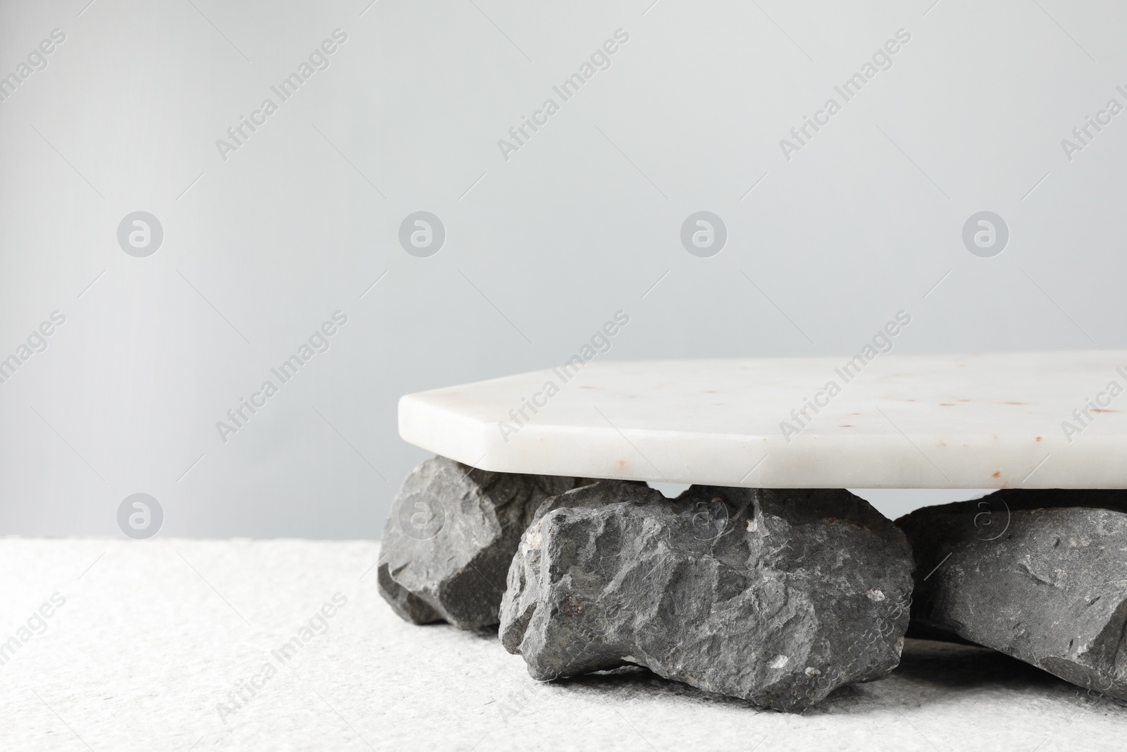 Photo of Presentation for product. Marble podium and stones on grey background. Space for text