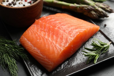 Photo of Fresh raw salmon and ingredients for marinade on black table, closeup