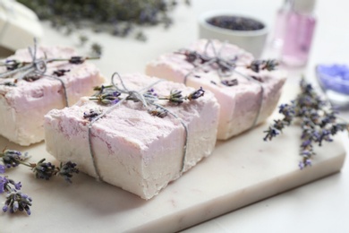Photo of Hand made soap bars with lavender flowers on cutting board, closeup
