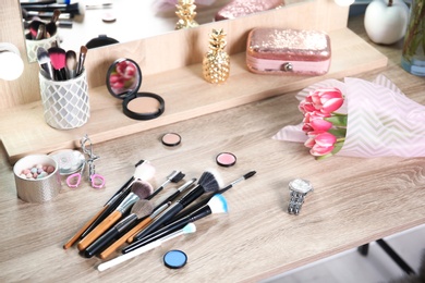 Photo of Professional brushes, makeup products and tulips on wooden table