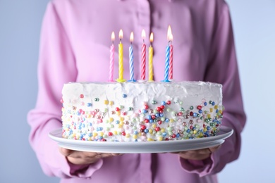 Photo of Woman holding birthday cake with burning candles, closeup