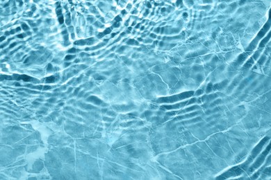 Rippled surface of clear water on light blue background, top view