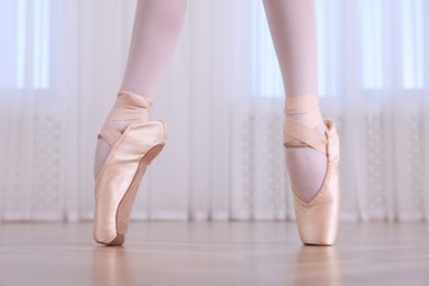 Photo of Little ballerina practicing dance moves in studio, closeup of legs