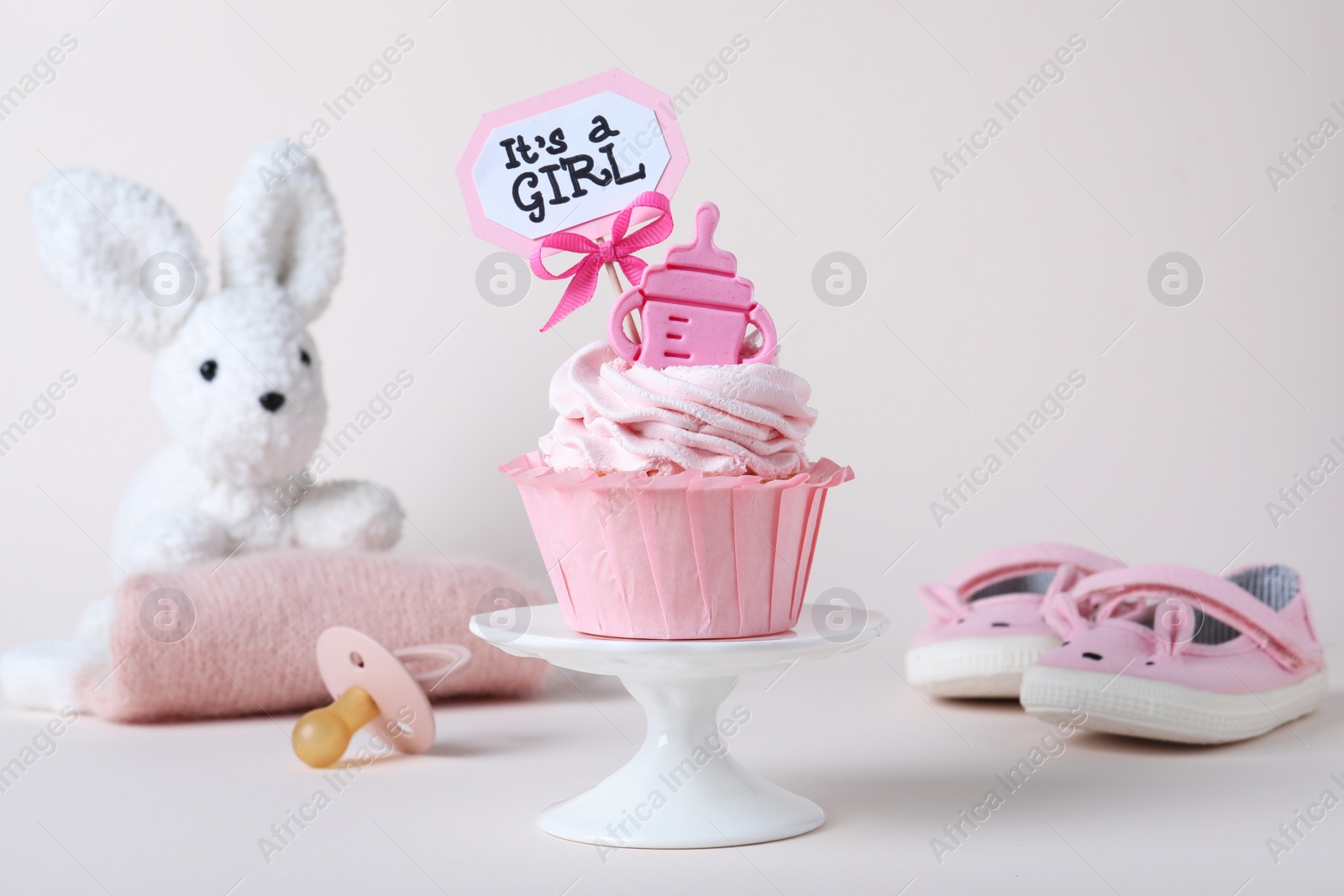 Photo of Beautifully decorated baby shower cupcake for girl with cream and topper on light background