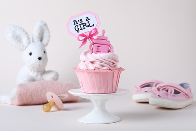 Photo of Beautifully decorated baby shower cupcake for girl with cream and topper on light background