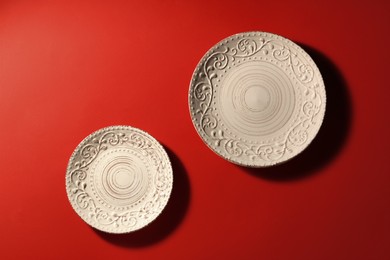 Photo of Clean ceramic plates on red background, flat lay