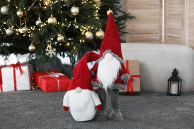 Photo of Cute Scandinavian gnomes on carpet near Christmas tree in room