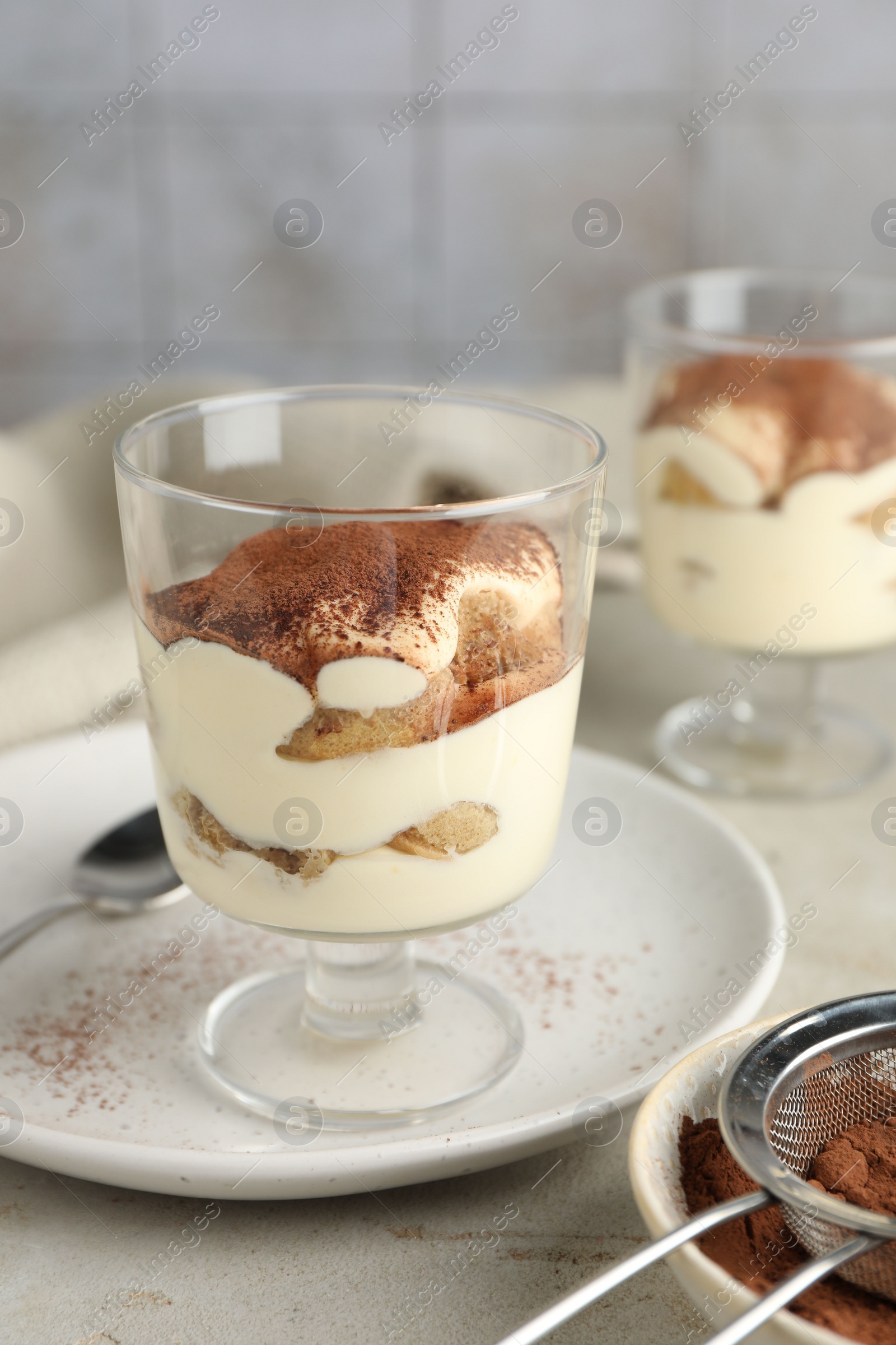 Photo of Delicious tiramisu in glass on light table