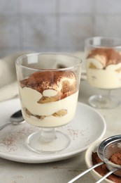 Photo of Delicious tiramisu in glass on light table