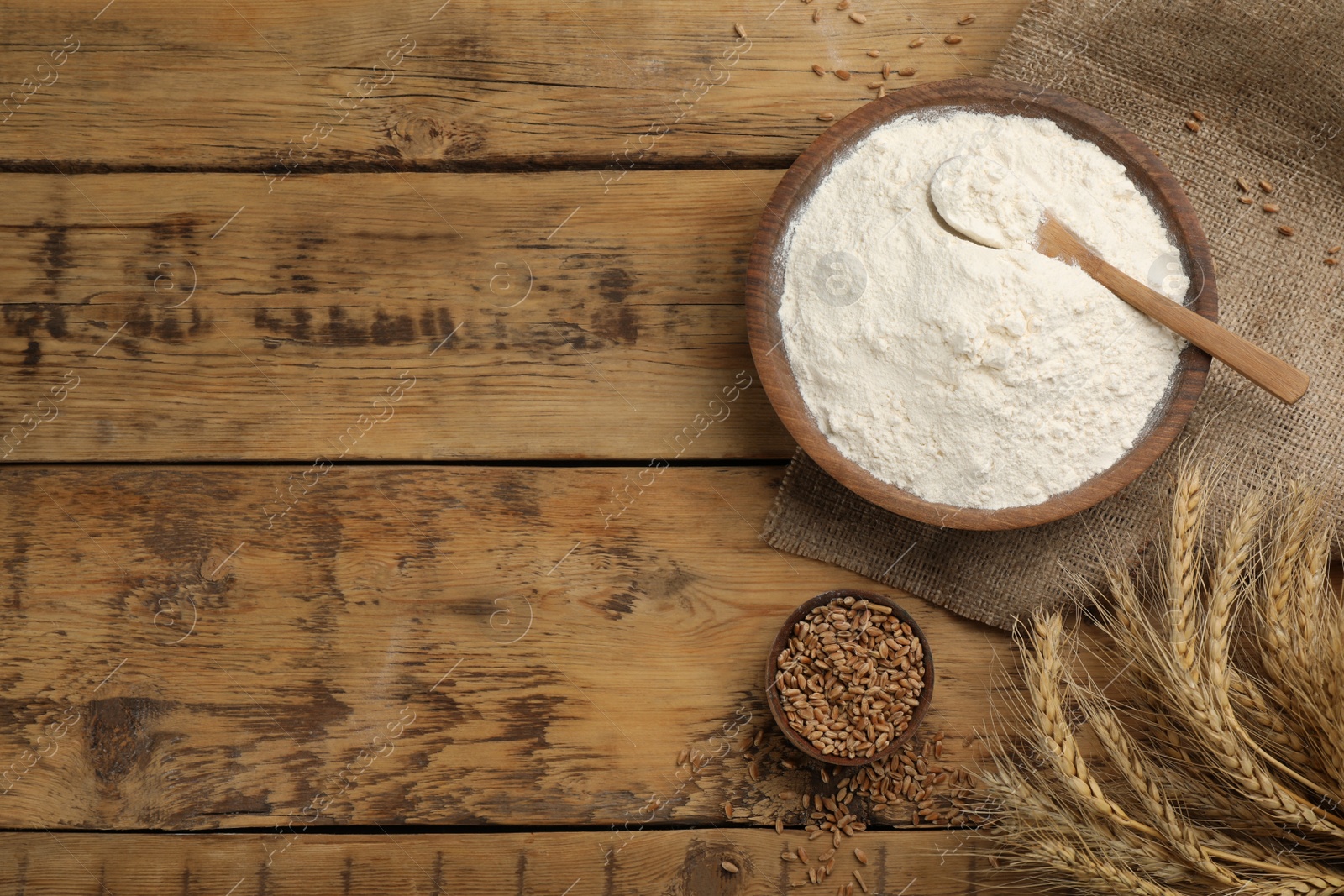 Photo of Flat lay composition with wheat flour on wooden table. Space for text