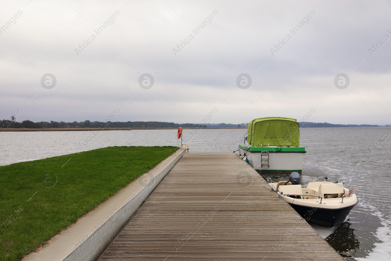 Photo of Wooden pier with moored boats near sea. Real estate