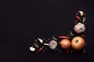 Photo of Flat lay composition with garlic, peppers and onions on black background. Space for text