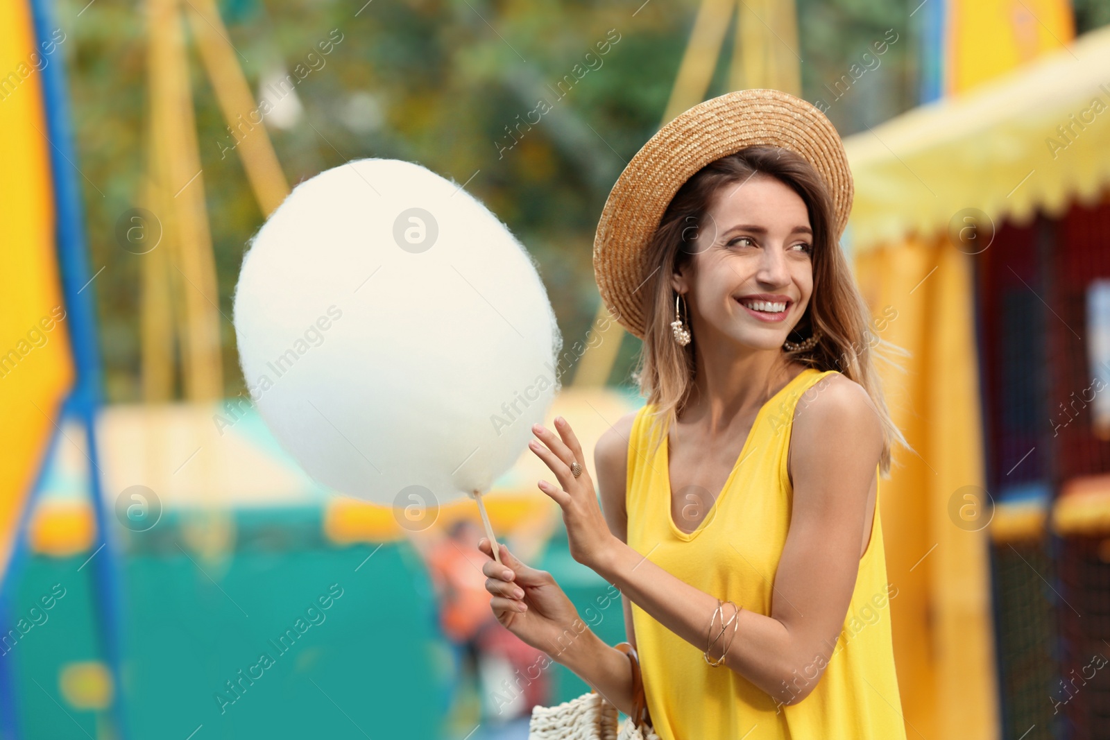 Photo of Happy young woman with cotton candy in amusement park