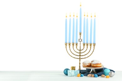 Photo of Hanukkah celebration. Composition with menorah, dreidels and gift boxes on table against white background