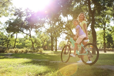 Photo of Happy mother teaching her daughter to ride bicycle in park