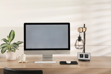 Photo of Modern computer with blank monitor screen and peripherals on wooden table indoors