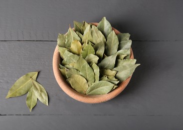 Photo of Aromatic bay leaves in wooden bowl on gray table, flat lay