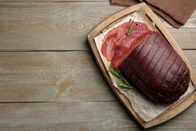 Photo of Tasty bresaola, peppercorns and rosemary on wooden table, top view. Space for text