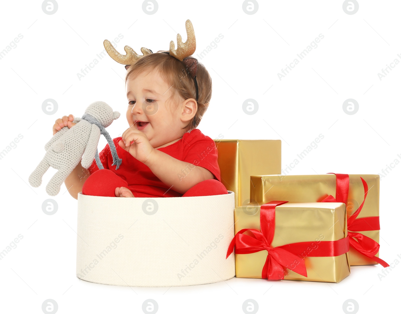 Photo of Festively dressed baby with Christmas gifts and toy on white background