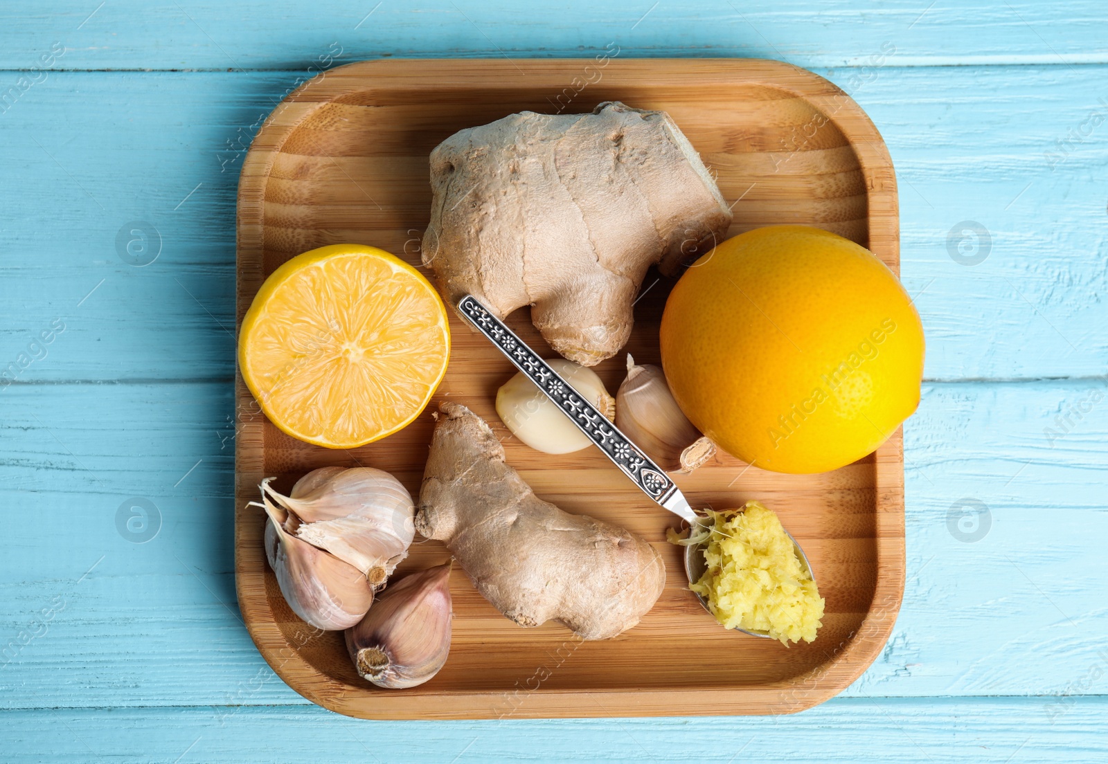 Photo of Fresh garlic and other natural cold remedies on light blue wooden table, top view