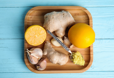 Photo of Fresh garlic and other natural cold remedies on light blue wooden table, top view