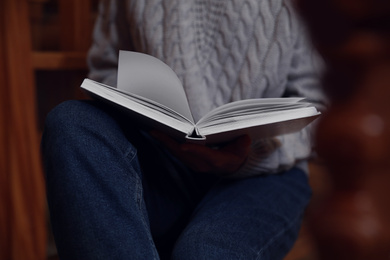 Photo of Woman reading book on stairs at home, closeup