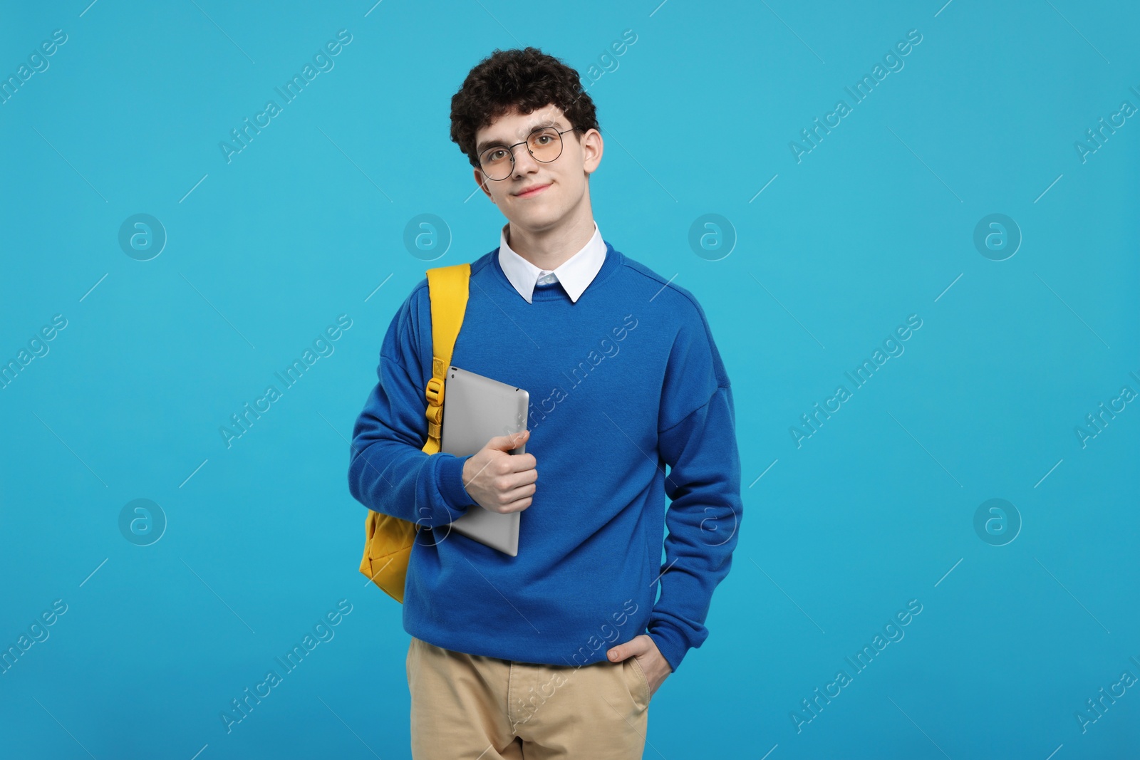 Photo of Portrait of student with backpack and tablet on light blue background