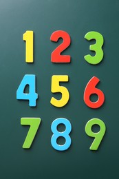 Colorful numbers on green background, flat lay