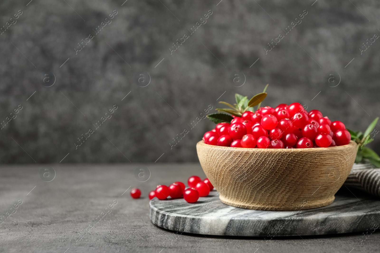 Photo of Tasty ripe cranberries on grey table, closeup. Space for text