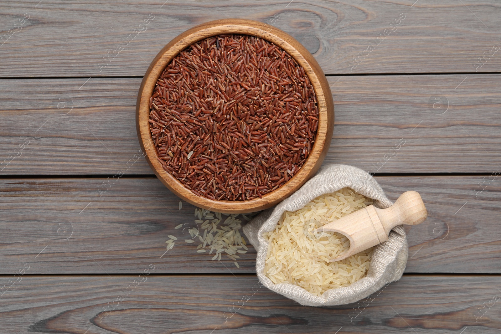 Photo of Bag and bowl with different sorts of rice on wooden table, flat lay