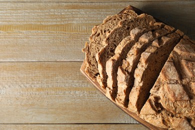 Photo of Freshly baked cut sourdough bread on wooden table, top view. Space for text