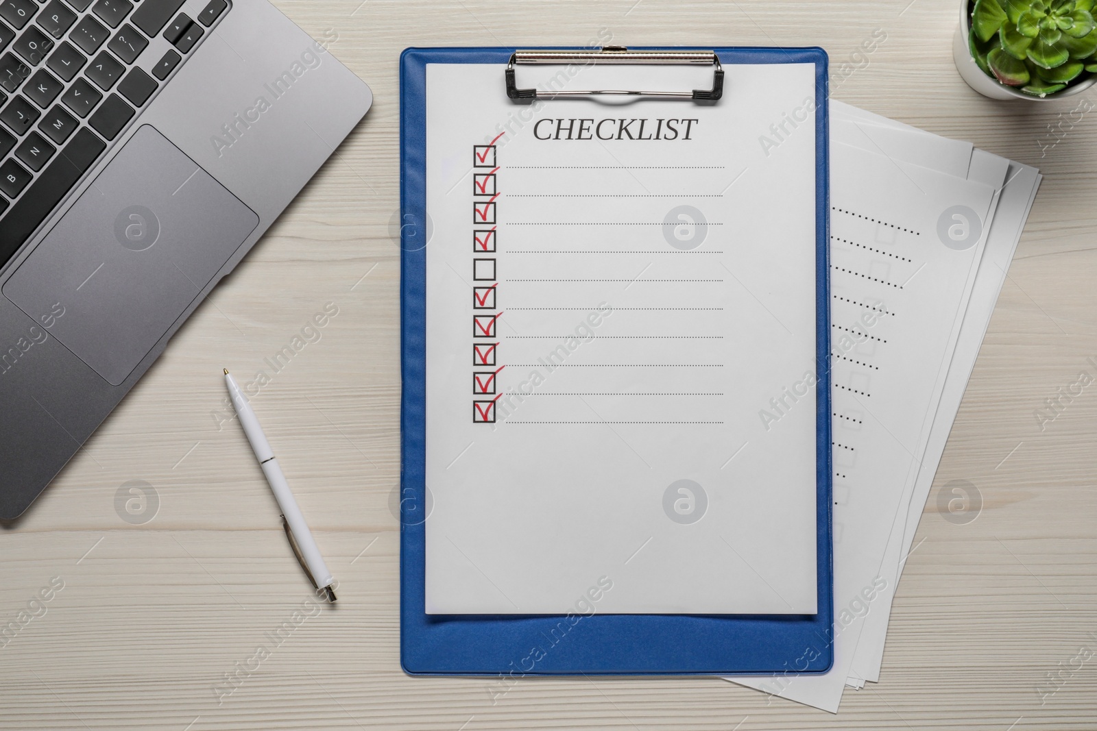 Photo of Clipboard with checklist, pen and laptop on wooden table, flat lay