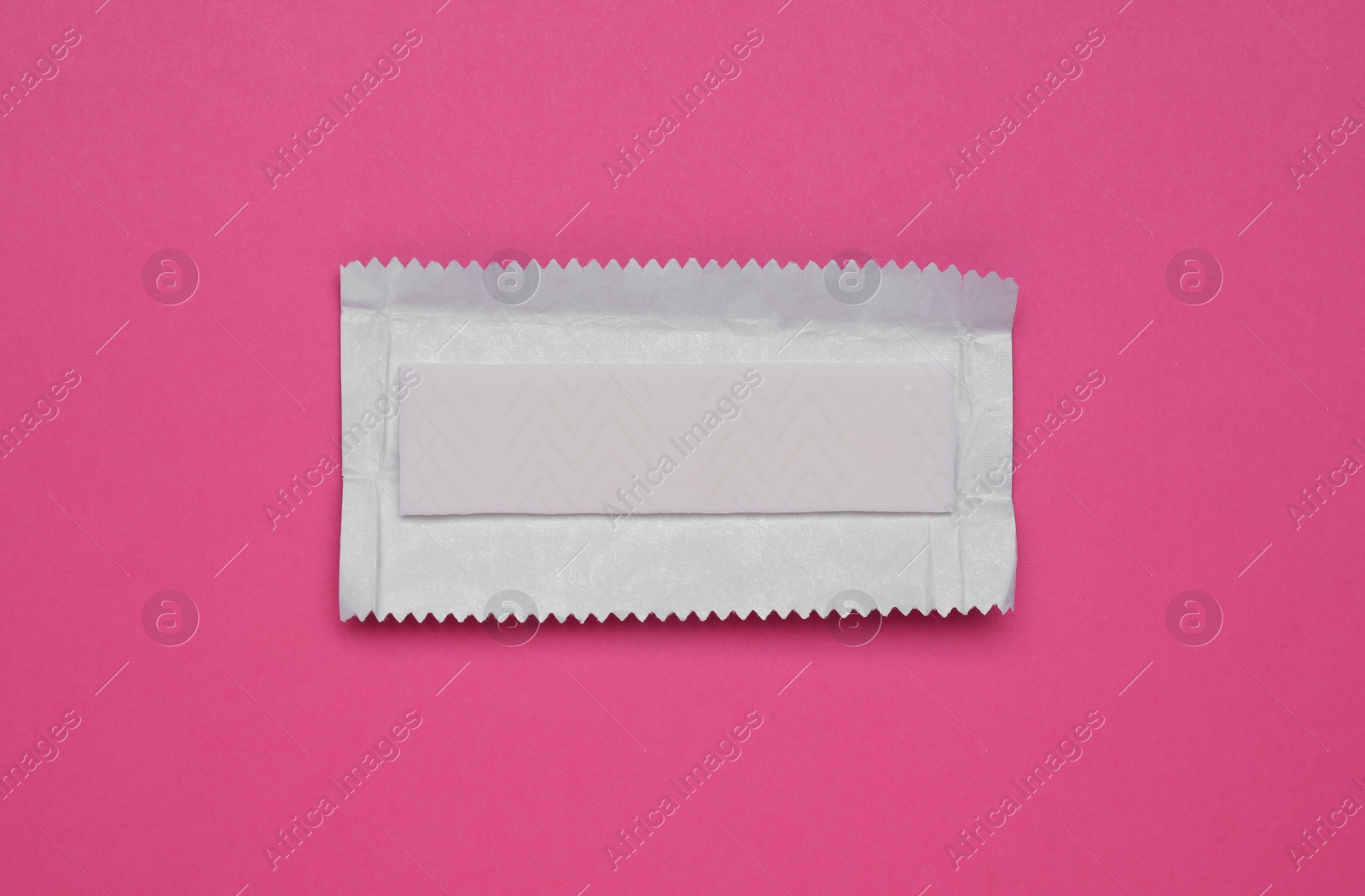 Photo of Unwrapped stick of tasty chewing gum on bright pink background, top view