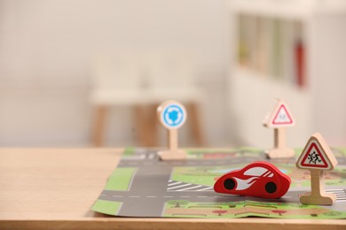 Photo of Set of wooden road signs and car on table indoors, closeup. Space for text. Children's toys