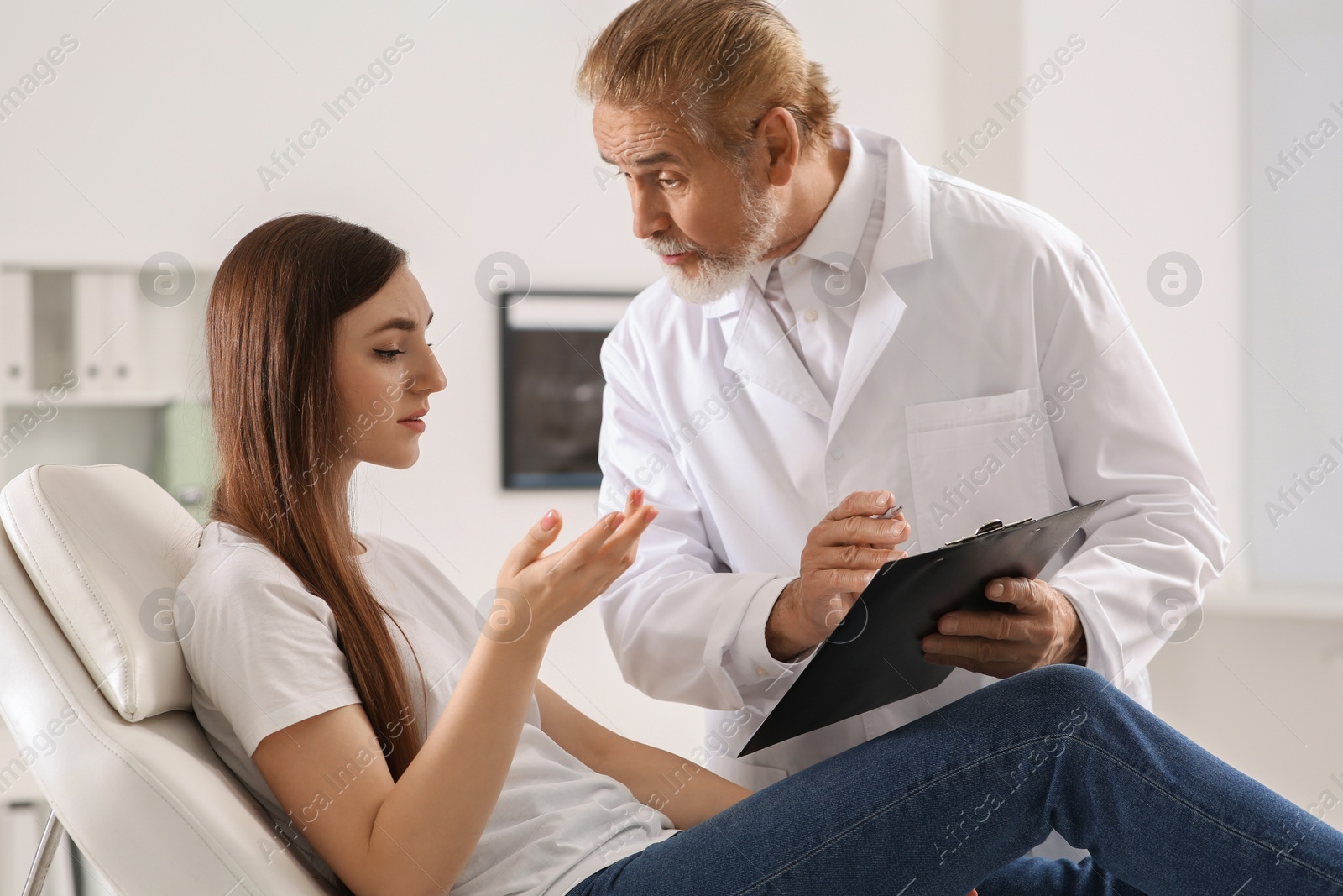 Photo of Professional orthopedist consulting young woman in clinic