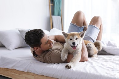 Happy man with his cute Akita Inu puppy at home