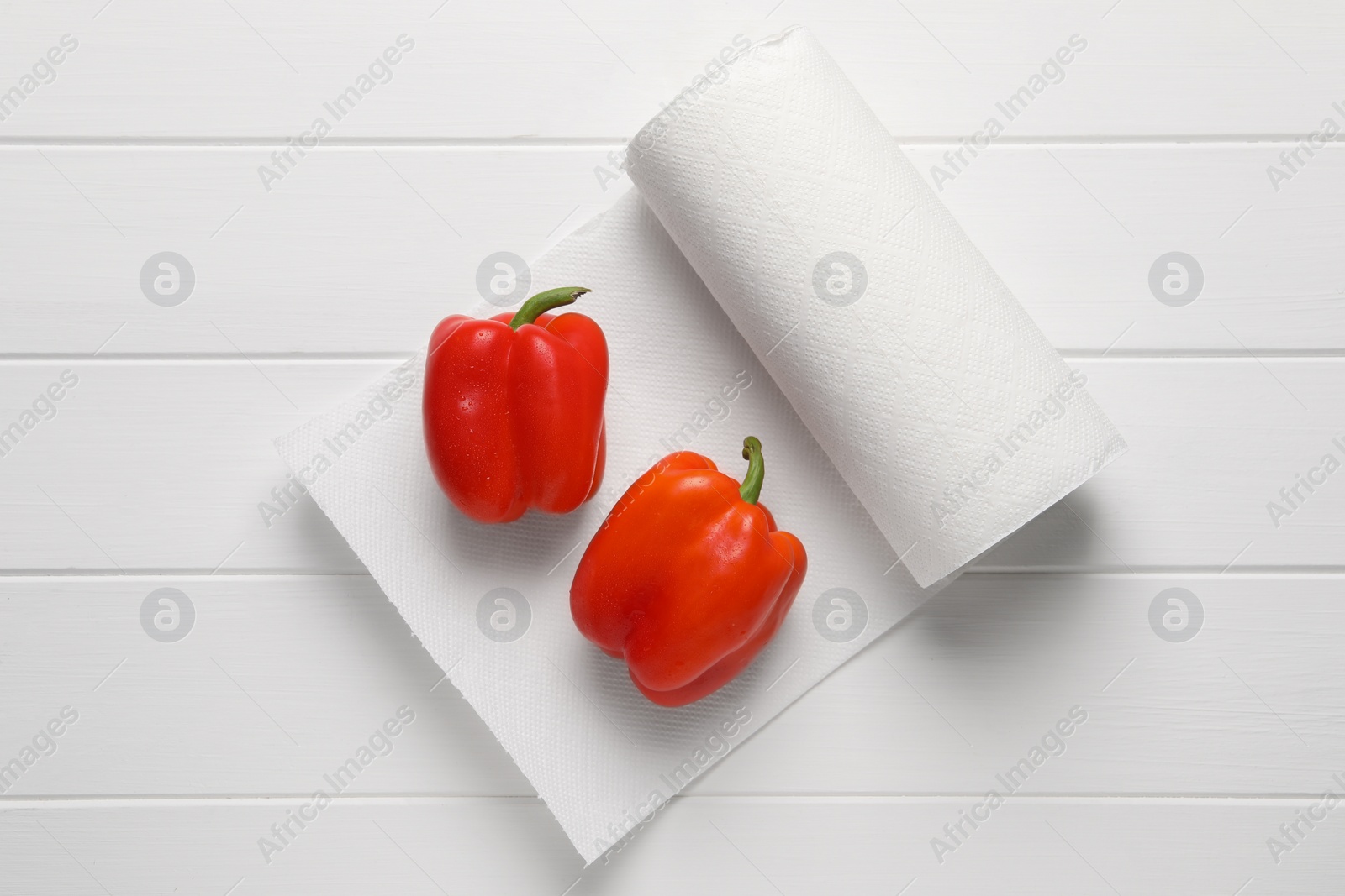 Photo of Roll of paper towels with bell peppers on white wooden table, top view